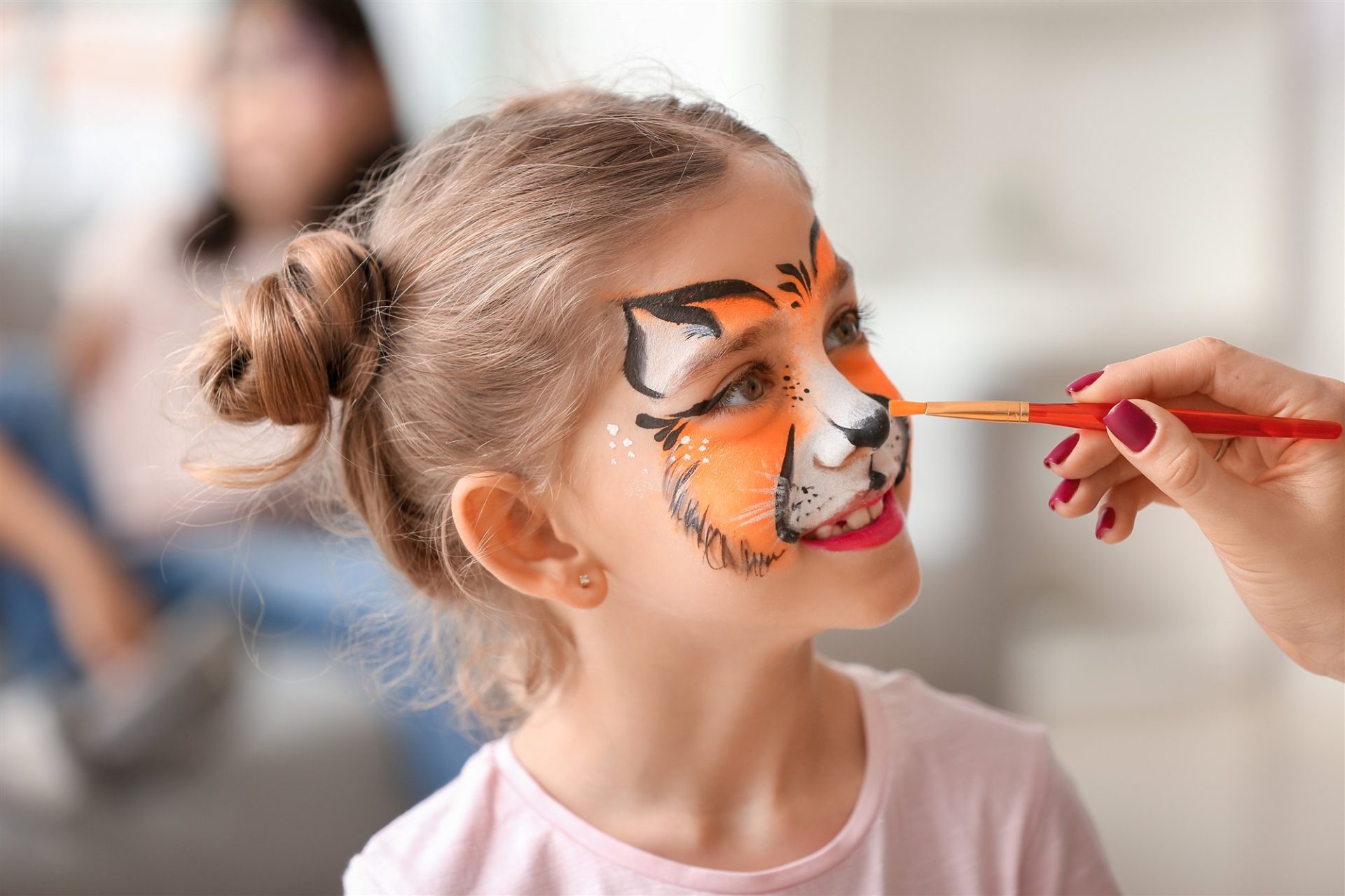 Barn får malet tigeransigt med ansigtsmaling