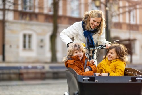 Mother checking on her children who is riding in the front section of a cargo bike